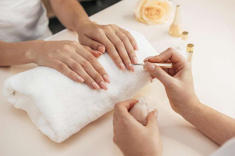 Mulher com manicure pintando as unhas.