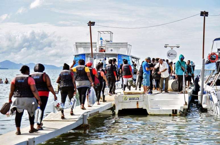 Grupo de migrantes embarca em lanchas em Necoclí, na Colômbia, para entrar na selva do Darién e continuar o trajeto por Panamá