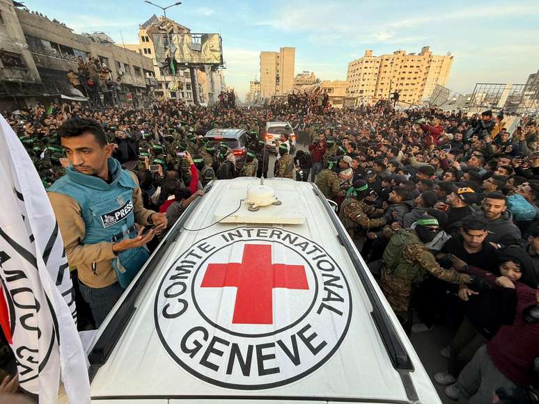 Palestinian Hamas militants and people gather around a Red Cross vehicle before the release of hostages kidnapped during the October 7, 2023, attack on Israel by Hamas, as part of a ceasefire and a hostages-prisoners swap deal between Hamas and Israel, in Gaza City, January 19, 2025