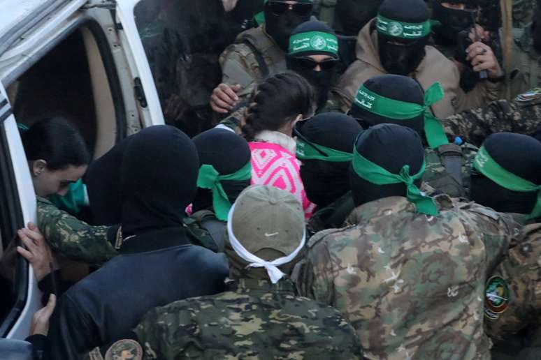 Palestinian Hamas militants hand over hostages kidnapped during the October 7, 2023, attack on Israel by Hamas, to members of the International Committee of the Red Cross (ICRC) as part of a ceasefire and a hostages-prisoners swap deal between Hamas and Israel, in Gaza City, January 19, 2025