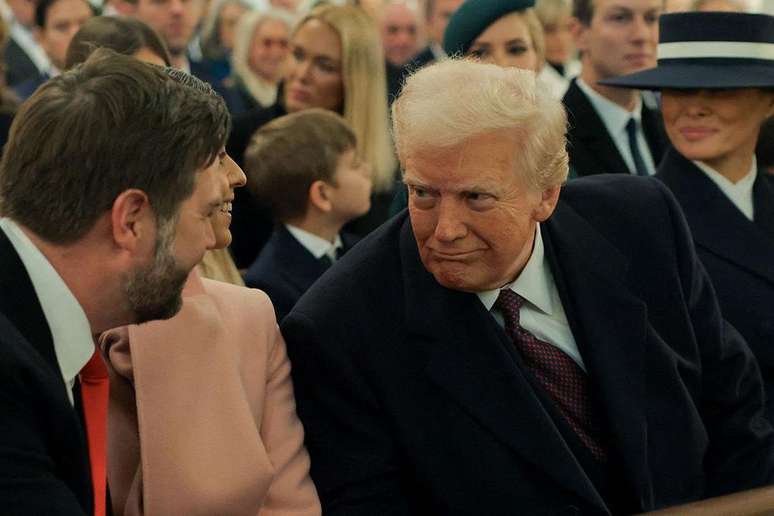 Donald Trump, ao lado de sua esposa Melania, conversa com J.D. Vance durante o culto na igreja