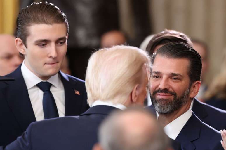 Donald Trump (de costas), com o filho caçula, Barron (esq.), e o mais velho, Donald Trump Jr (dir.)