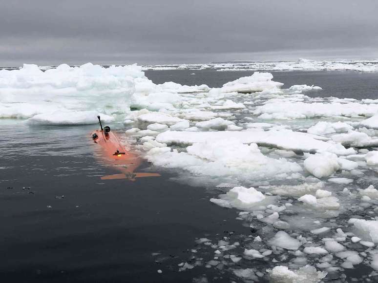 Submarino robótico laranja movendo-se através de blocos de gelo.