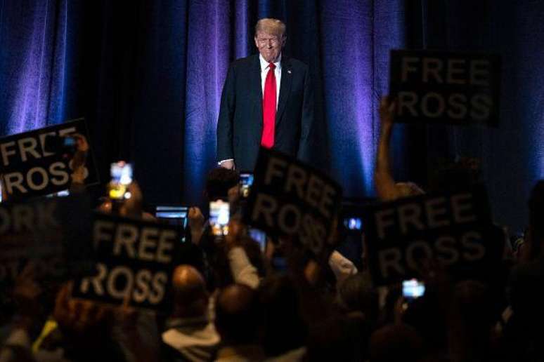 Pessoas seguram cartazes com os dizeres "Libertem Ross" enquanto o então candidato Donald Trump chega para discursar na Convenção Nacional Libertária em Washington, no dia 25 de maio de 2024