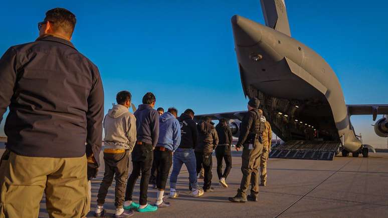 Migrantes sendo embarcados em avião para deportação nos Estados Unidos