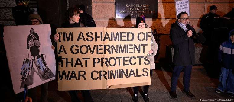 Protesto em Varsóvia: "Tenho vergonha de um governo que protege criminosos de guerra", diz cartaz em inglês