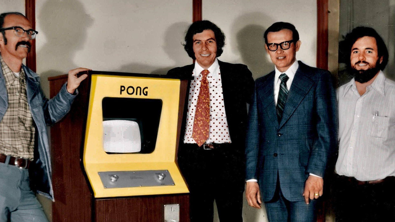 Os fundadores da Atari, Ted Dabney (esquerda), Nolan Bushnell, Fred Marincic e Al Alcorn posam com uma máquina Pong, 1972