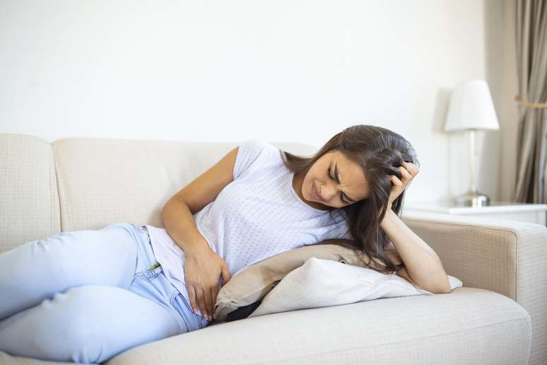 Mulher deitada no sofá com inchaço abdominal 