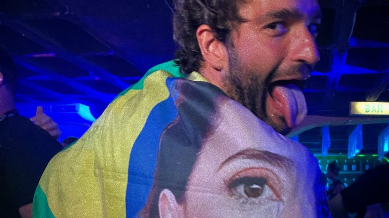 Humberto Carrão se enrola em bandeira com rosto de Fernanda Torres