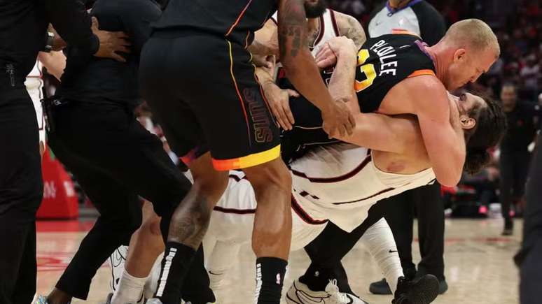 Mason Plumlee e Steven Adams caindo no chão agarrados durante uma briga