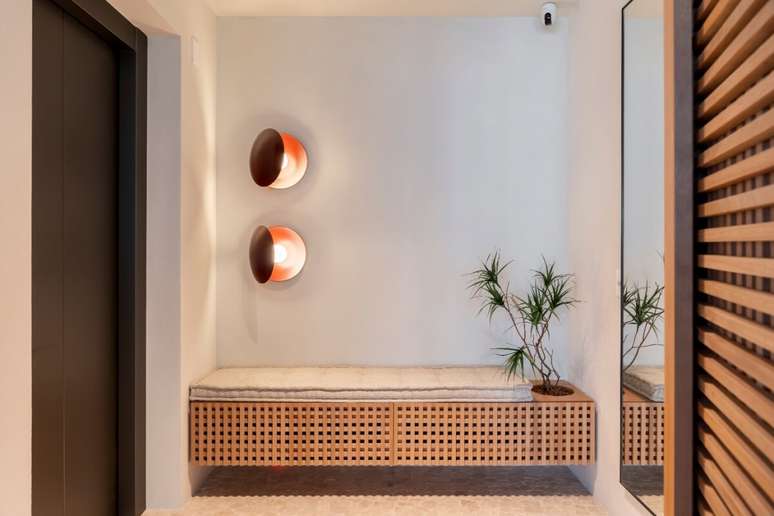 O banco suspenso com portas em muxarabi une estética, funcionalidade e ventilação no hall Projeto: Rawi Arquitetura + Design |