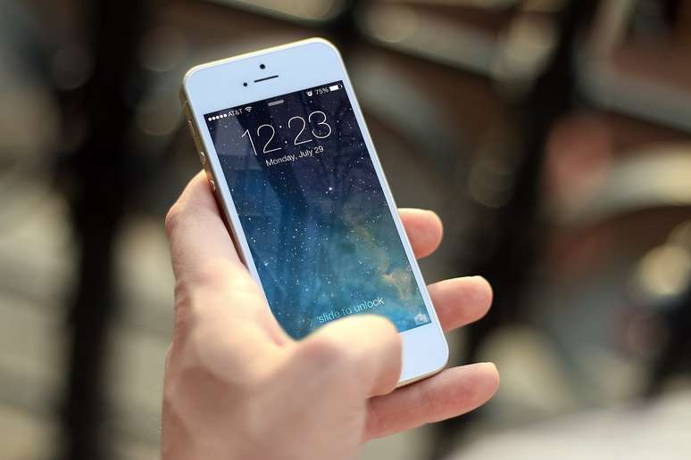Mão de uma pessoa segurando iPhone branco.