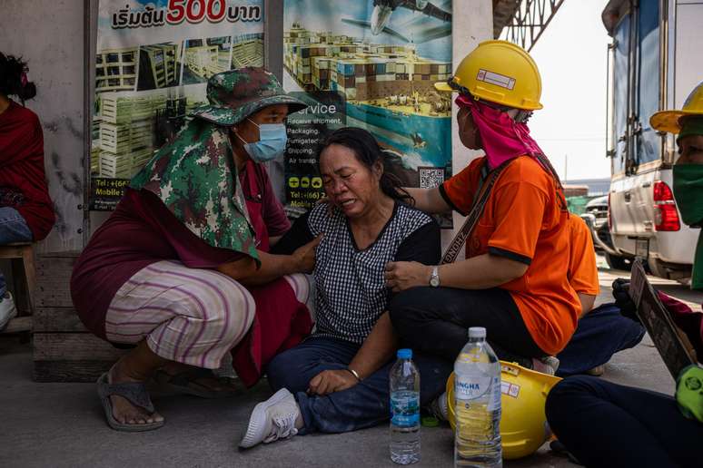 Pessoas choram ao lado de um prédio que desmoronou perto do Mercado Chatuchak, na Tailândia.