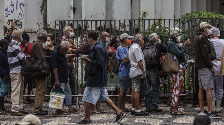 Pessoas em fila para receber doação de comida no Rio durante a pandemia; Kalache aponta que período evidenciou desigualdades sociais, incluindo as que afetam os idosos