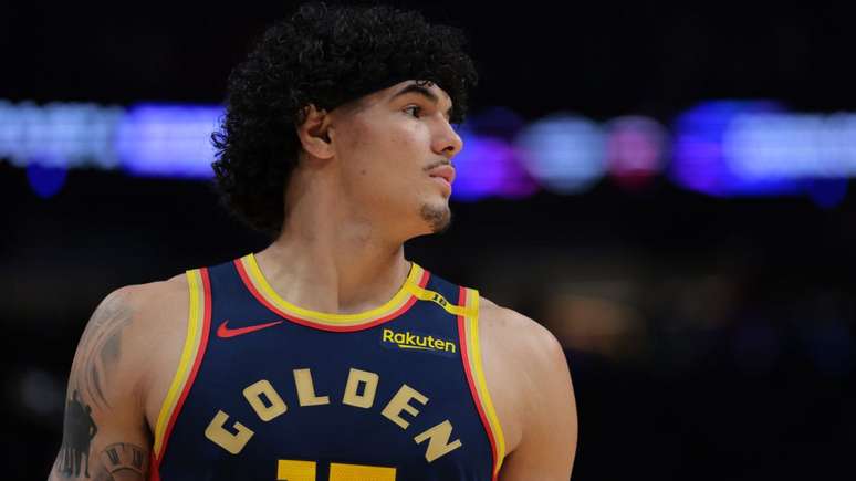 Gui Santos olhando para o lado com uma vestindo a camisa azul escuro do Golden State Warriors