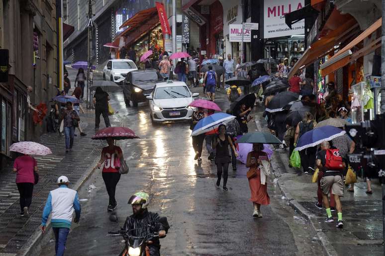 Pedestres enfrentam chuva no cruzamento da Ladeira Porto Geral com a rua 25 de Março, região de comércio popular no Centro de São Paulo, na tarde desta quinta-feira, 3.