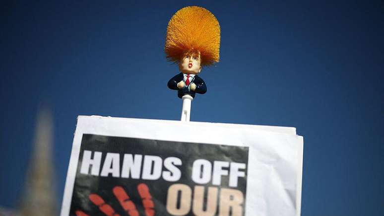 Manifestante em Londres segura uma escova de vaso sanit&aacute;rio com a imagem de Trump