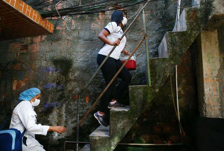 Duas mulheres sobem escada em área externa de casa