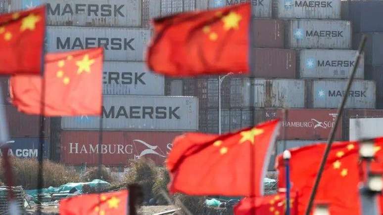 Bandeiras da China em frente a cont&ecirc;ineres 