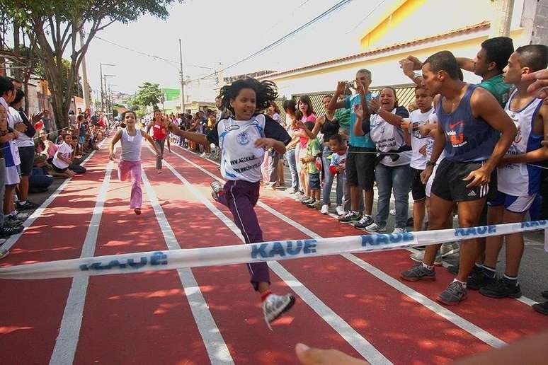 As corridas na rua mobilizam Itaquera. Fran está à direita, de shorts preto e regata azul, incentivando na linha de chegada..