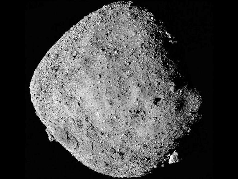Um asteroide rochoso e empoeirado contra um fundo escuro.