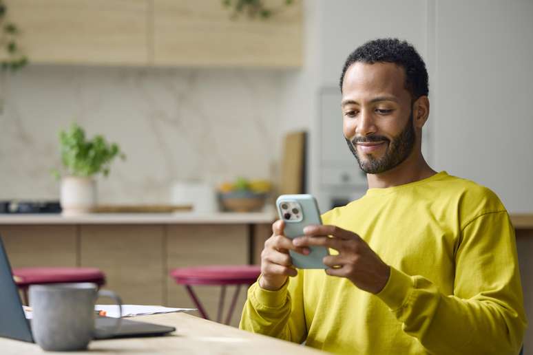 Jovem sorridente usando um smartphone. 
