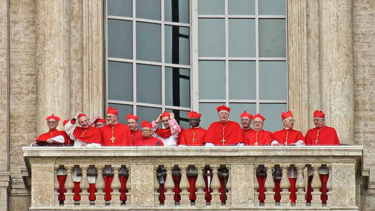 Cardeais vestindo ternos vermelhos na sacada da Basílica de São Pedro após a eleição do novo Papa. Procedimento eleitoral também conhecido como conclave papal ou reunião do Colégio Cardinalício no Vaticano em 19 de abril de 2005.