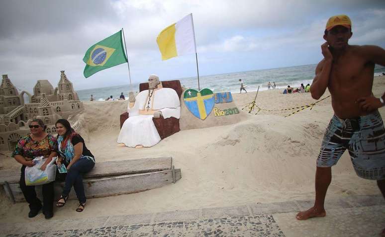 Em Copacabana, em 2013, turistas tiram foto com homenagem a Francisco, que escolheu o Brasil como seu primeiro destino fora da Itália como papa