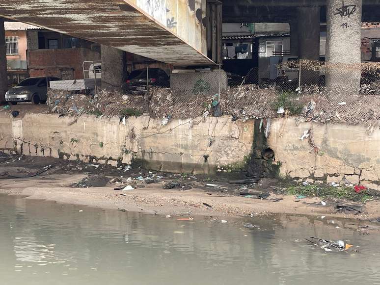 Lixo acumulado no rio Faria-Timbó mostra o quanto a água sobre nas enchentes em Manguinhos, o pior problema climático da comunidade.