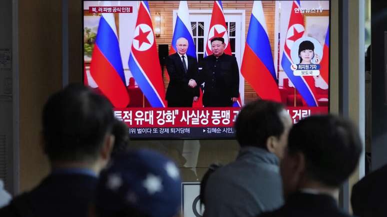 Uma tela de TV em Seul mostra uma imagem de arquivo de um encontro entre o líder norte-coreano Kim Jong-un, (à dir.), e o presidente russo, Vladimir Putin, em Pyongyang.