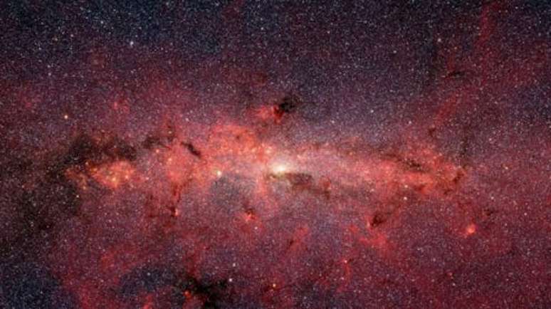 Imagem de formação de estrelas no centro da Via Láctea: fenômenos de ionização de gases e emissão de radiação da densa região central da galáxia podem ser explicados por um tipo de matéria escura mais "leve" que a usualmente buscada pelos cientistas Susan Stolovy (SSC/Caltech) et al., NASA SPitzer/IRAC