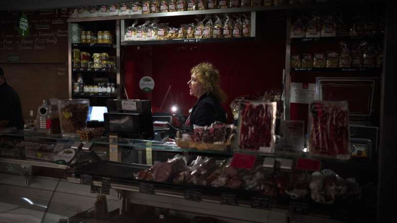 Vendedores usam a luz de seus celulares para selecionar e registrar alimentos durante o apagão em Barcelona, ​​Espanha, na segunda-feira, 28 de abril de 2025.
