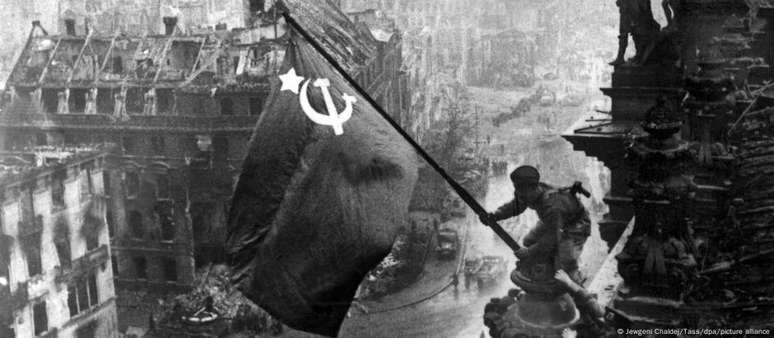 I ngrianghraf cáiliúil a mhéadaigh propaganda na Rúise, an saighdiúir Trasula Bandeira ag barr an Reichstag an 2 Bealtaine, 1945, Lá Capitulation Belim