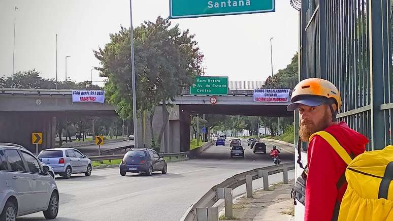 Entregador na ponte da Casa Verde, na Marginal Tiet&ecirc;, zona norte da capital paulista, com faixas de protesto em 1&ordm; de Maio.