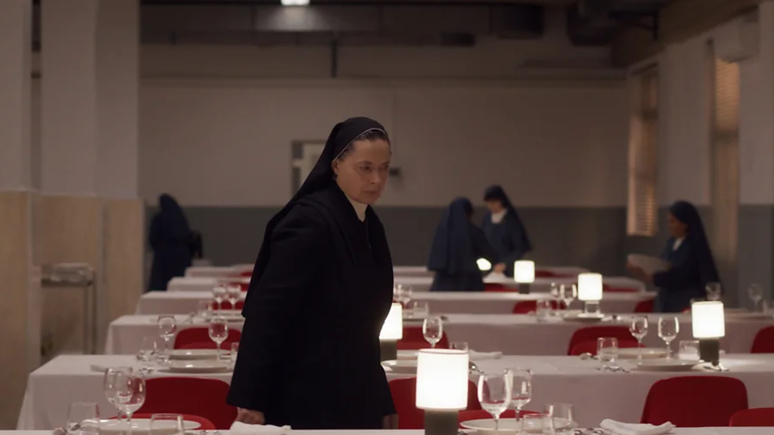 Cena do filme Conclave (2024), no qual a irmã Agnes checa o refeitório onde os cardeais farão as refeições