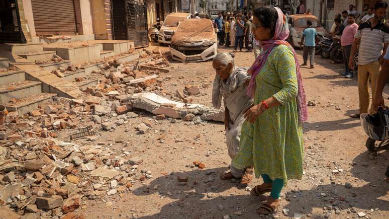 Mulheres caminham em direção à casa destruída, após a operação militar do Paquistão contra a Índia, em Rehari, Jammu, em 10 de maio de 2025