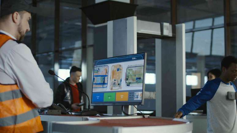 Funcion&aacute;rio da alf&acirc;ndega do aeroporto observando a varredura de malas na seguran&ccedil;a