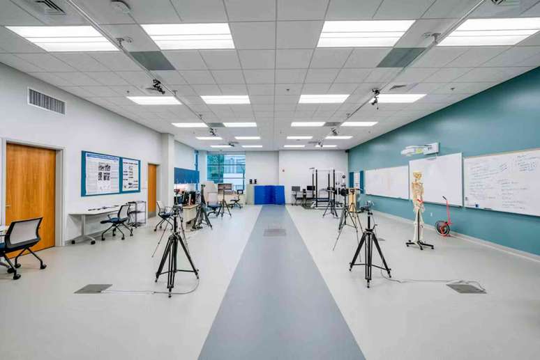 Uma sala grande com uma faixa cinza no centro do piso, com uma placa quadrada no meio e c&acirc;meras em trip&eacute;s ao longo dela.