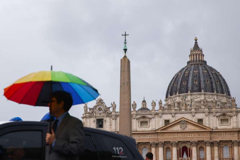 Imagem ilustrativa de homem com guarda-chuva com as cores do arco-íris em frente ao Vaticano
