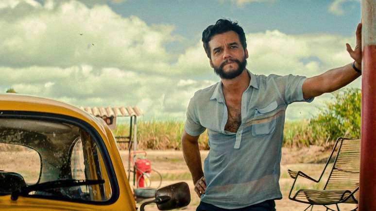 Wagner Moura apoiado em um poste