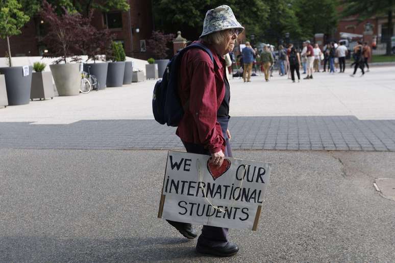 Le linn agóid Harvard i gcoinne ionsaithe Trump, iompraíonn an agóideoir póstaer a deir: 'Is breá linn ár gcuid mac léinn idirnáisiúnta'