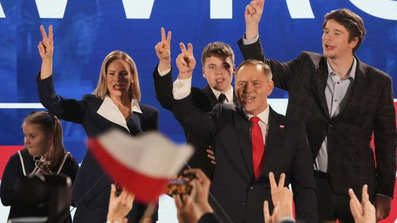 O candidato presidencial Karol Nawrocki, um historiador conservador apoiado pelo partido de direita Lei e Justiça, segundo à direita, cumprimenta os apoiadores em sua sede após o segundo turno da eleição presidencial em Varsóvia, Polônia, domingo, 1º de junho de 2025.