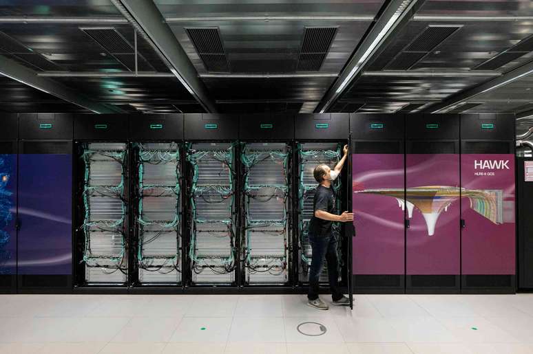 Foto de um homem abrindo um rack de servidores de computador.
