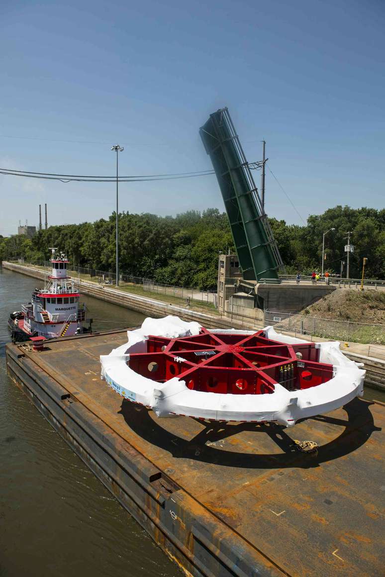 Foto de um grande dispositivo em forma de roda em uma barca&ccedil;a em um rio.