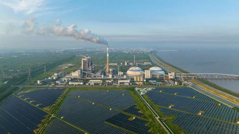 Campo de painéis solares perto de uma usina energética movida a carvão, em Xangai, na China