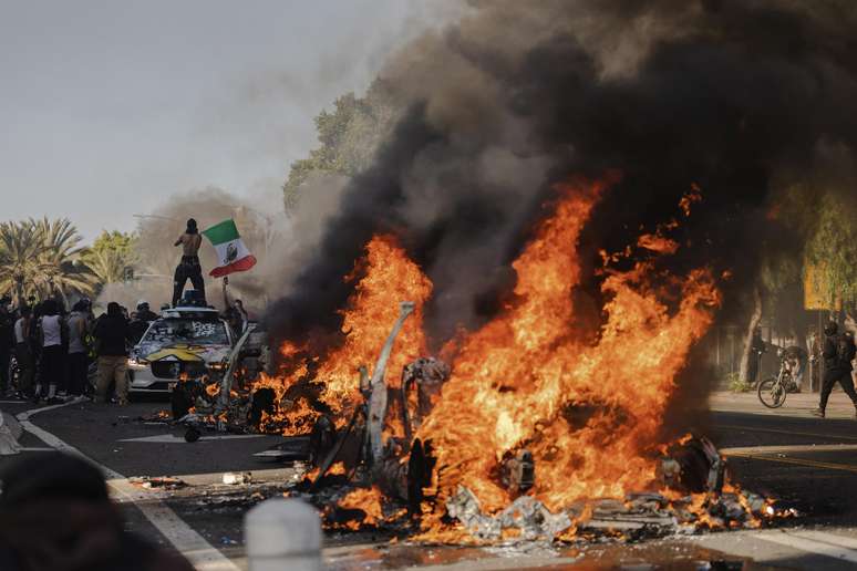 ários carros pegam fogo em uma rua ao norte de Los Angeles durante confrontos entre manifestantes e a polícia em 8 de junho de 2025 no centro de Los Angeles, Califórnia.