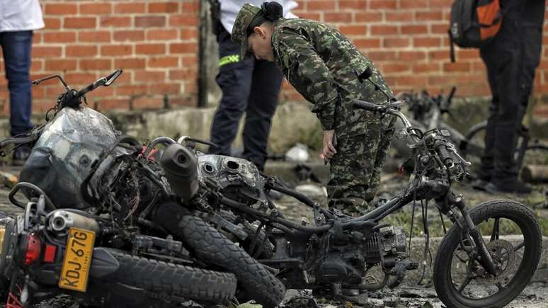 Um soldado colombiano inspeciona os restos de motos em Cali, Colômbia, em 10 de junho de 2025, após a explosão de uma bomba.