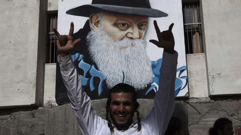 Um judeu ultraortodoxo em frente a grafite com rosto do rabino Menachem Mendel Schneerson na cidade Sderot, no sul de Israel, vizinha &agrave; Faixa de Gaza; a foto &eacute; de 2010