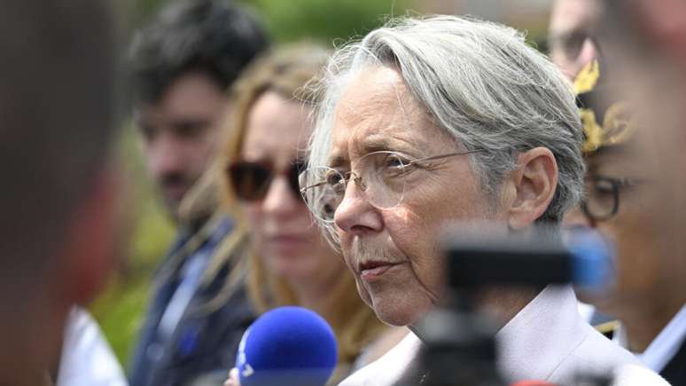 A ministra francesa da Educação, Elisabeth Borne, conversa com jornalistas diante da escola Françoise-Dolto, em Nogent, no nordeste da França, na quarta-feira (11), um dia após a morte de uma inspetora por um aluno do local.