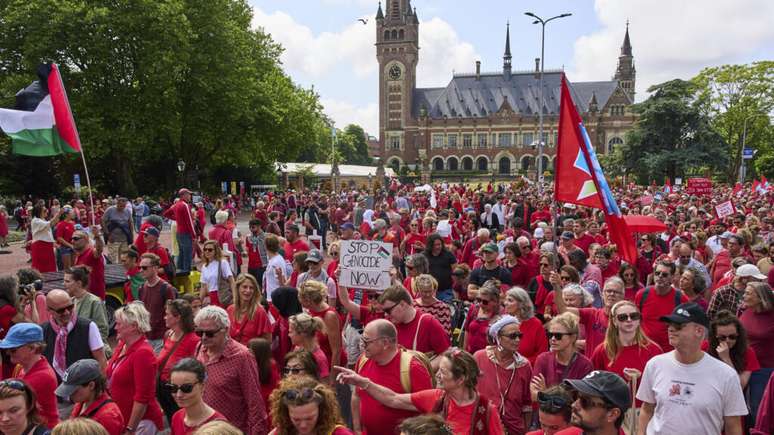 Manifestantes vestidos de vermelho marcharam do lado de fora do Palácio da Paz, sede do Tribunal Internacional de Justiça, em Haia.